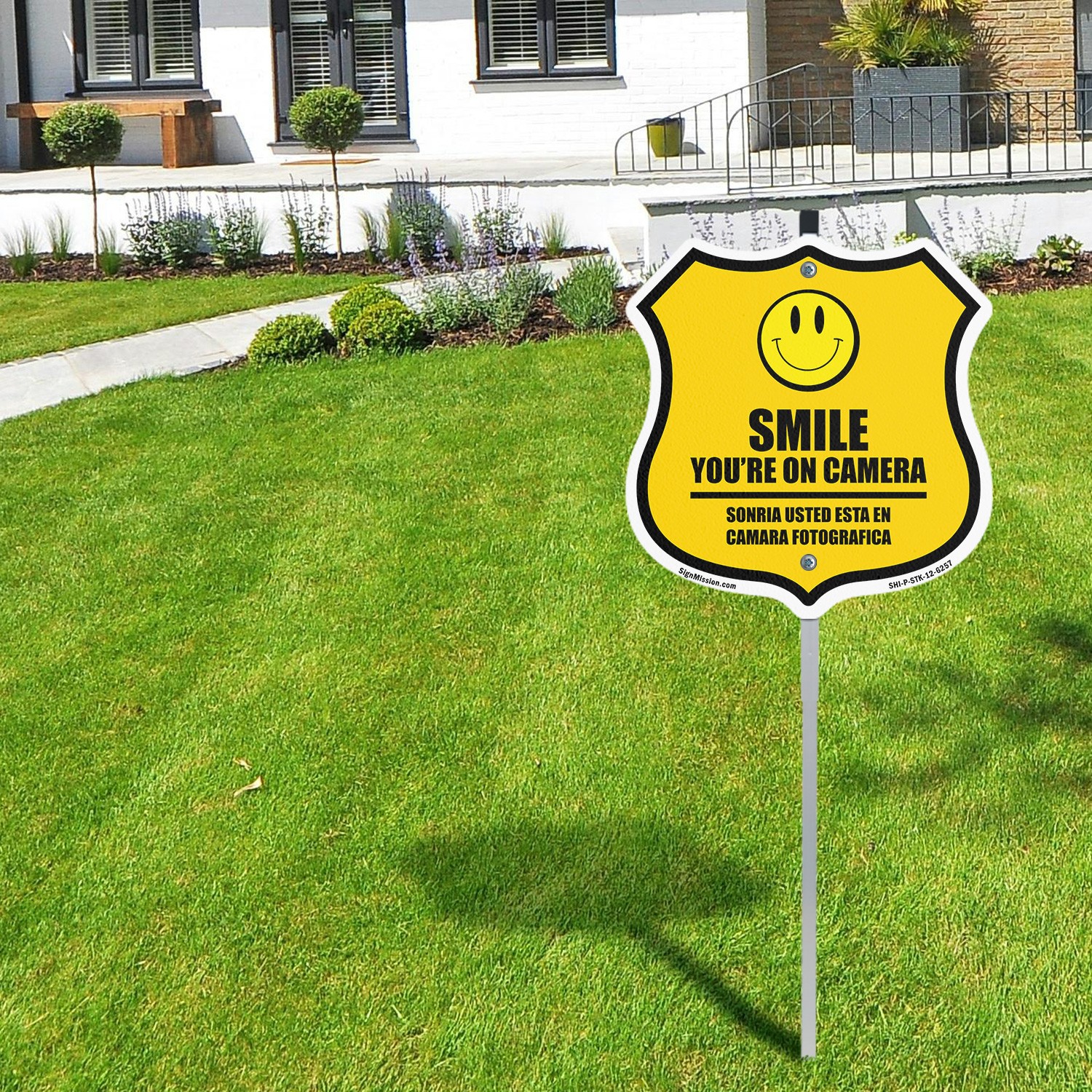 Smile You&rsquo;re On Camera Bilingual English / Spanish Shield Shaped Sign With Stake